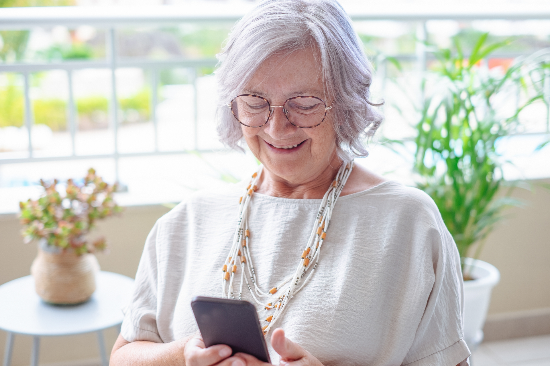 Adulta mayor sonriendo mientras mira su teléfono